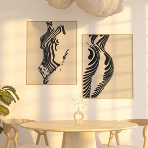 Könnte beinhalten: Zwei Schwarz-Weiß-Abstrakte Linienkunst-Drucke einer menschlichen Figur im minimalistischen Stil, die an einer weißen Wand über einem Holztisch mit zwei Stühlen hängen.