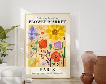 May include: A framed art print featuring a floral design with the text "Flower Market Paris." The artwork showcases colorful flowers in shades of yellow, orange, purple, and blue against a beige background. The print is displayed in a room with neutral tones.