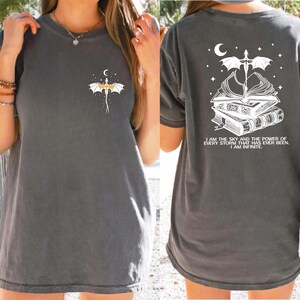 a woman wearing a gray t-shirt with a dragon design and a quote on the back.