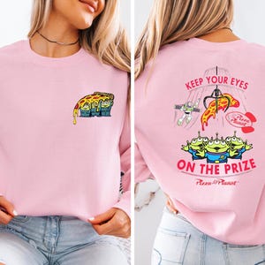 A woman wearing a pink long-sleeved shirt with a cartoon pizza design and text on the back.