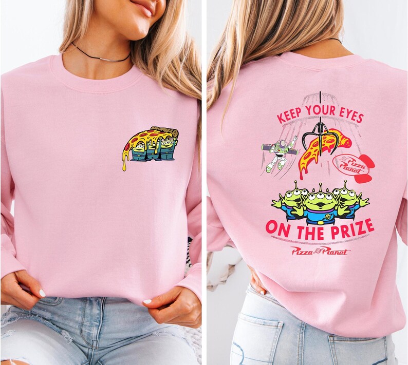 A woman wearing a pink long-sleeved shirt with a cartoon pizza design and text on the back.
