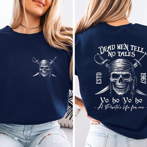 A woman wearing a navy blue t-shirt with a pirate-themed design on the back.