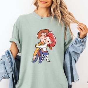 a woman wearing a t - shirt with a picture of a boy hugging a girl
