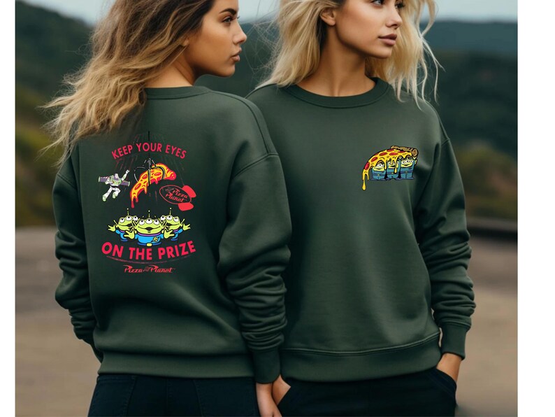 two women wearing green sweatshirts with colorful graphics and text.