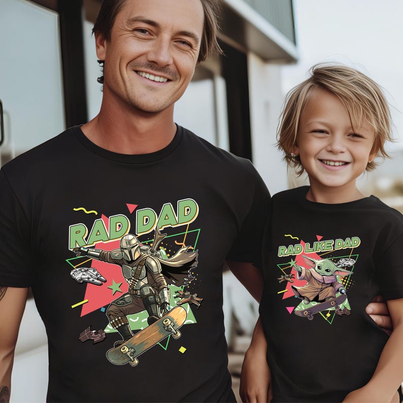 A man and a young boy wearing black t-shirts with a graphic design featuring a character from the Star Wars franchise.