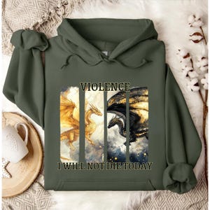 May include: An olive green hoodie featuring a graphic of two dragons, one gold and one black, separated by vertical lines. The word "VIOLENCE" is above the dragons, and "I WILL NOT DIE TODAY" is below.