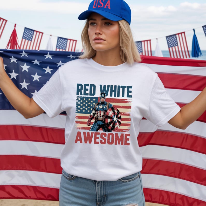A woman wearing a white t-shirt with a graphic of a superhero and the text "RED WHITE AWESOME" stands in front of an American flag.
