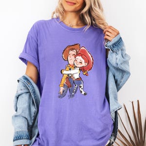 a woman wearing a purple t - shirt with a picture of two people hugging