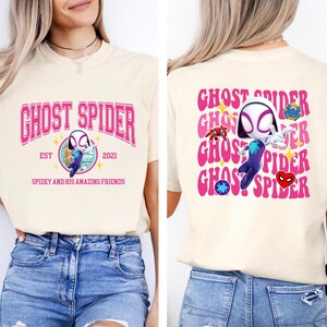 a woman wearing a white t-shirt with a graphic design of a character from the Spider-Man franchise.