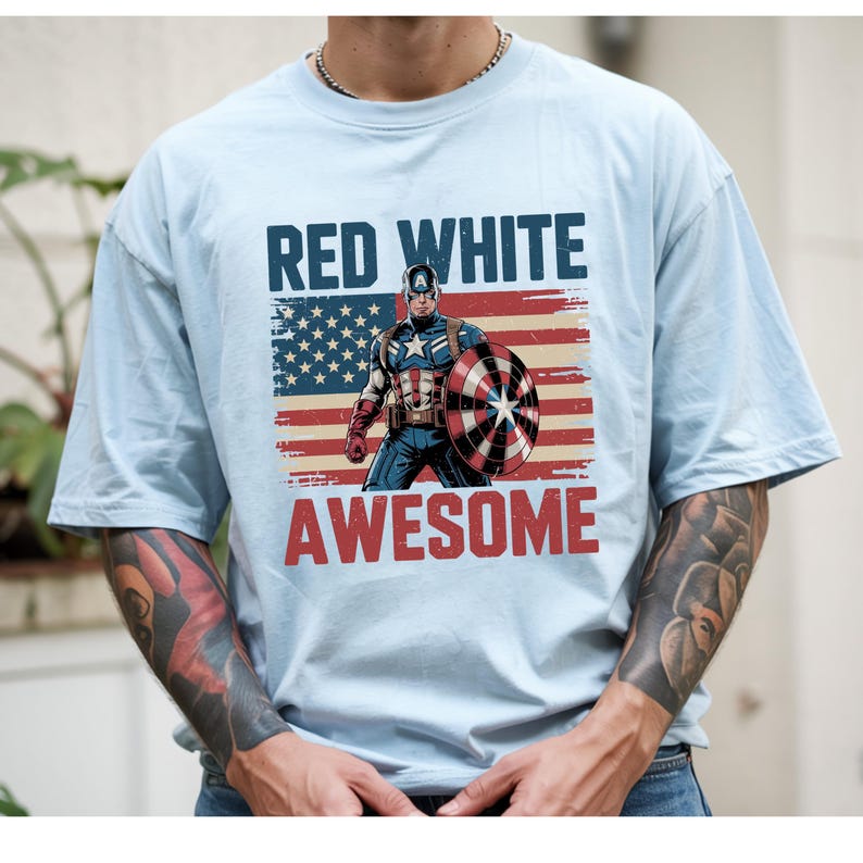 A person wearing a t-shirt with a graphic design featuring a superhero character and the text "RED WHITE AWESOME" printed on it.