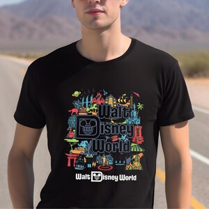 A man wearing a black t-shirt with a colorful graphic design featuring various Disney-themed illustrations and text.