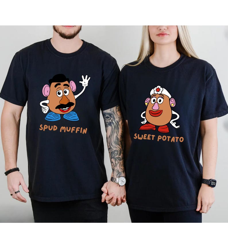 A man and a woman wearing black t-shirts with cartoon characters printed on them.