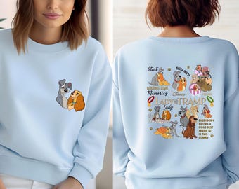 May include: Light blue sweatshirt featuring a graphic of Lady and Tramp on the front and a collage of characters and text from the movie on the back. The text includes "Start Building Some Memories" and "Everybody Knows a Dogs Best Friend is This Human."