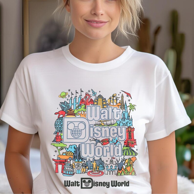 A woman wearing a white t-shirt with a colorful graphic design featuring various Disney-themed illustrations.