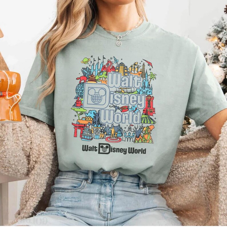 A person wearing a green t-shirt with a graphic design of various Disney landmarks and the text "Walt Disney World" printed on it.