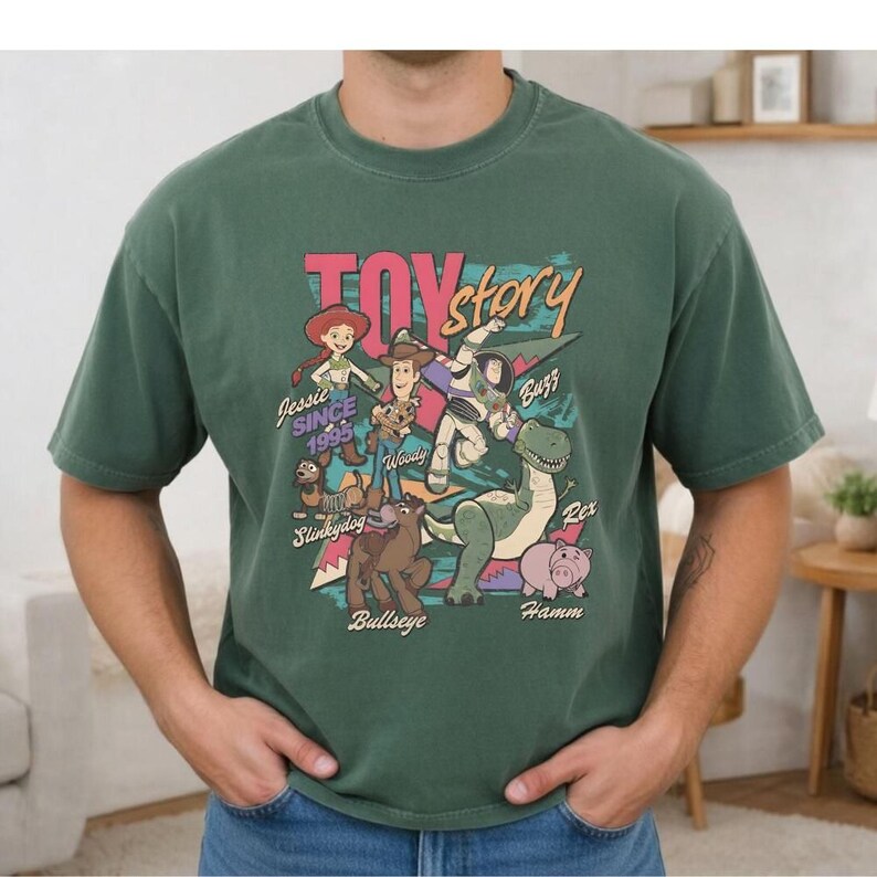 A green t-shirt with a colorful graphic design featuring characters from the Toy Story movie, including Woody, Buzz Lightyear, and other beloved characters.