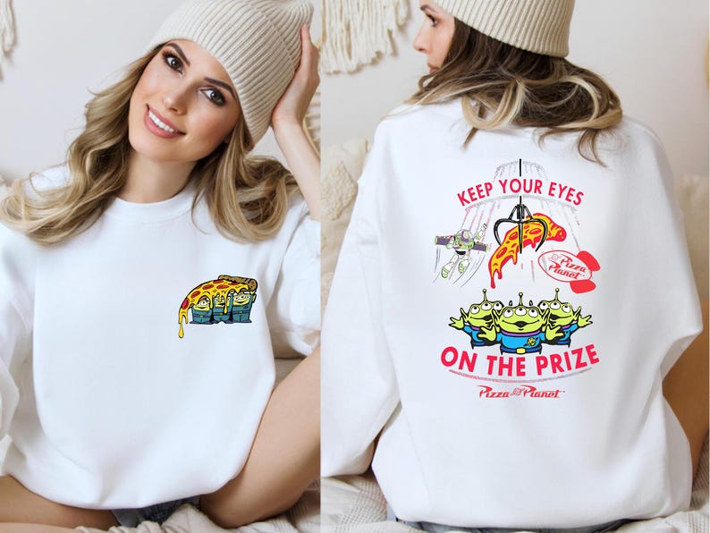 A woman wearing a white sweater with a cartoon pizza design and text on the back.