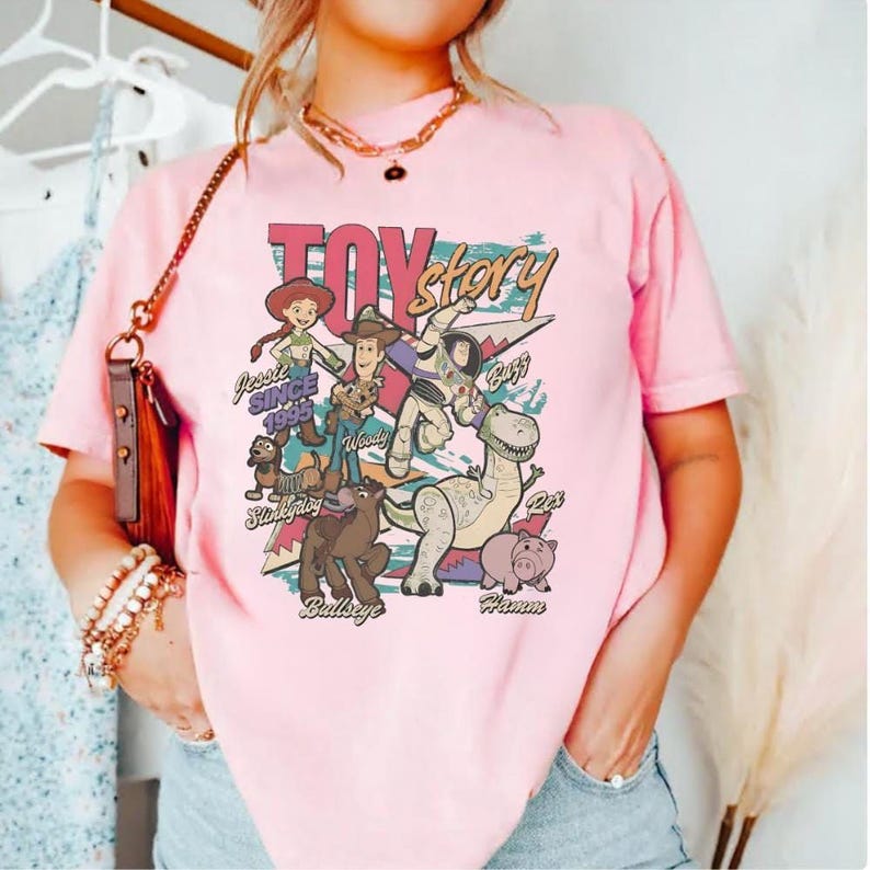 A woman wearing a pink t-shirt with a graphic design featuring characters from the Toy Story movie.