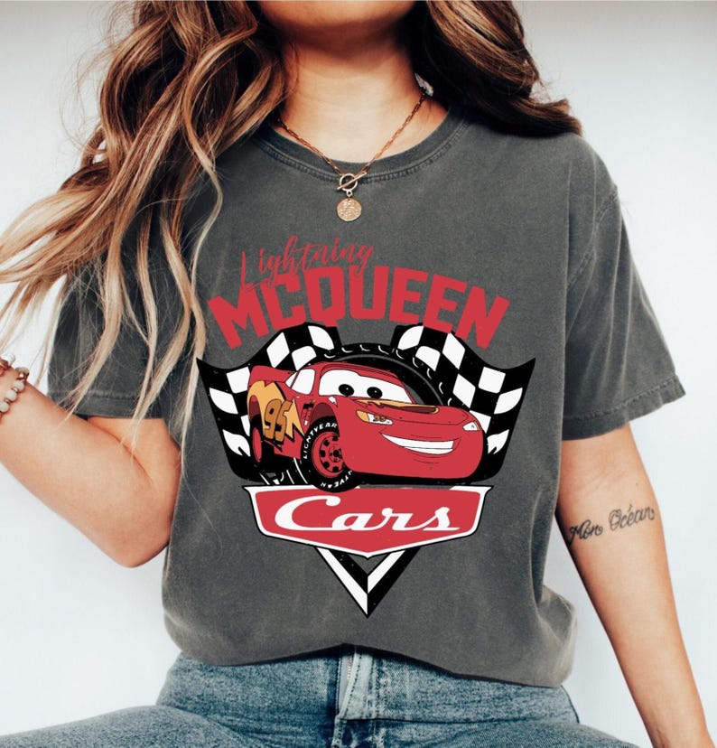 Puede incluir: Camiseta gris oscuro con Lightning McQueen de la pel&iacute;cula Cars. El dise&ntilde;o incluye un coche de carreras rojo con el n&uacute;mero 95, banderas a cuadros y la palabra "Cars" en blanco.