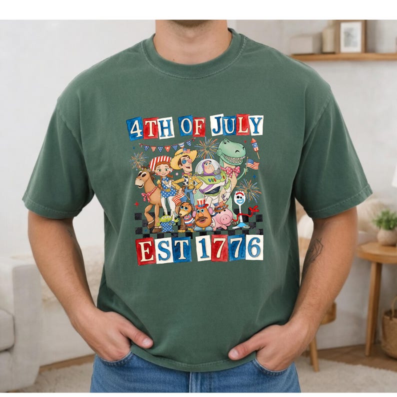 A green t-shirt with a graphic design depicting characters from the Toy Story franchise celebrating the 4th of July, including Woody, Buzz Lightyear, and other beloved characters.