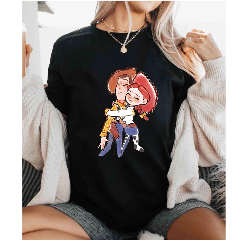 a woman wearing a black t - shirt with a picture of two people hugging