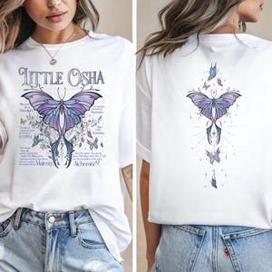 A woman wearing a white t-shirt with a butterfly design and text printed on it.