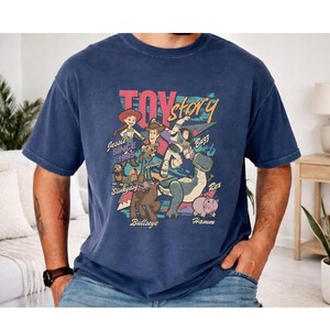 A man wearing a blue t-shirt with a colorful graphic design featuring characters from the Toy Story movie.