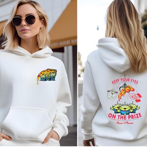 A woman wearing a white hoodie with a graphic design on the front and back.