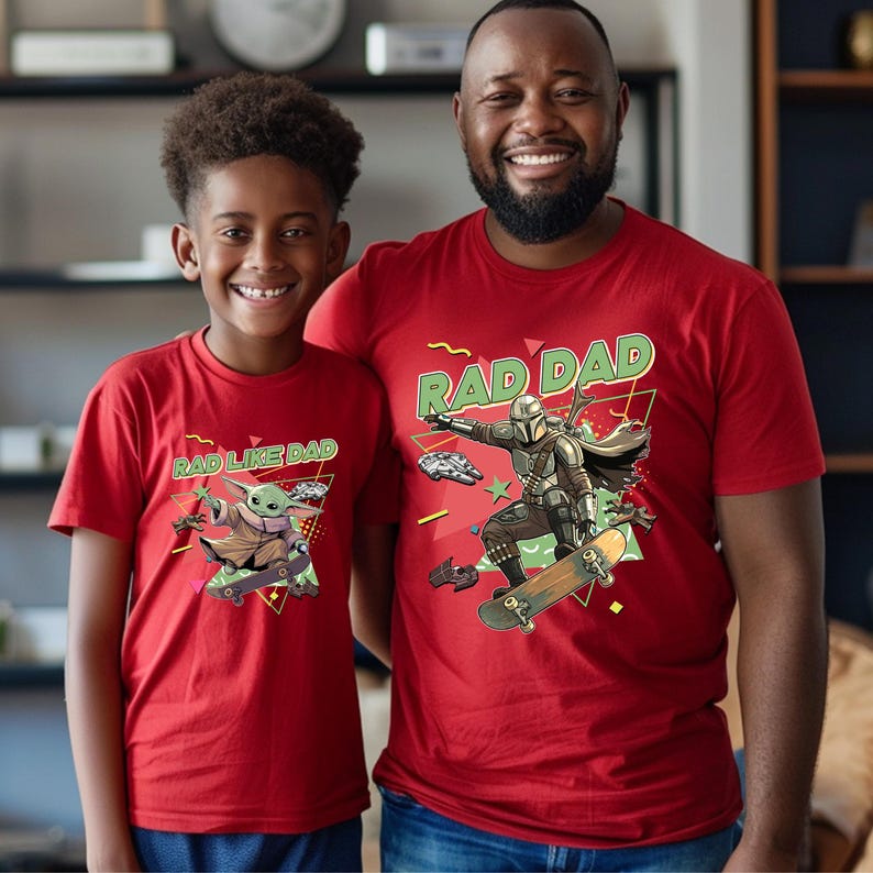A young boy and an adult man wearing red t-shirts with a graphic of a character from the Star Wars franchise, specifically the character Baby Yoda.