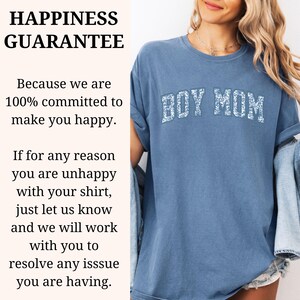 K&ouml;nnte beinhalten: Ein blaues T-Shirt mit dem Text "BOY MOM" in wei&szlig;en floralen Buchstaben. Das Shirt hat eine lockere Passform und ist aus einem weichen Material. Das Bild enth&auml;lt auch den Text "HAPPINESS GUARANTEE".