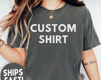 Pode incluir: Uma camiseta cinza escuro com as palavras "CUSTOM SHIRT" em letras brancas grandes. A camiseta tem gola redonda e mangas curtas. A palavra "PEPPER" está em uma caixa branca no canto inferior direito.