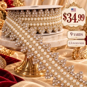 May include: A gold-toned trim ribbon featuring a central row of white pearls flanked by scalloped edges of clear rhinestones. The spool measures 9 yards in length and 1.3 inches in width, with text on the image indicating $34.99, 9 yards, and 1.3 inches wide.