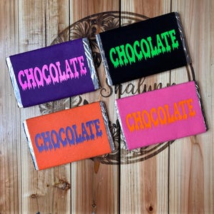 May include: Four chocolate bar wrappers with the word "CHOCOLATE" printed in dripping letters. The wrappers are in different colors: purple with pink letters, black with green letters, orange with blue letters, and pink with orange letters.