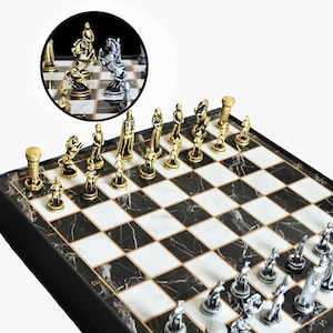 May include: A black and white marble chessboard with gold and silver chess pieces. The chess pieces are detailed and have a medieval theme.