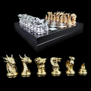 Könnte beinhalten: Ein Schachbrett aus schwarzem und weißem Marmor mit goldenen und silbernen Drachen-Schachfiguren. Das Schachbrett ist geschlossen und die Figuren sind in der Ausgangsposition angeordnet. Das Schachbrett befindet sich auf einer schwarzen Oberfläche.