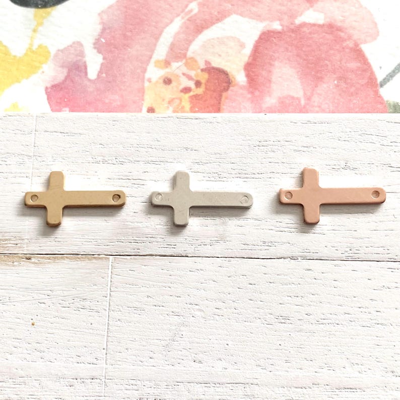 May include: Three metal cross charms in different finishes: gold, silver, and rose gold. The crosses are simple and elegant, perfect for adding a touch of faith to jewelry or crafts.