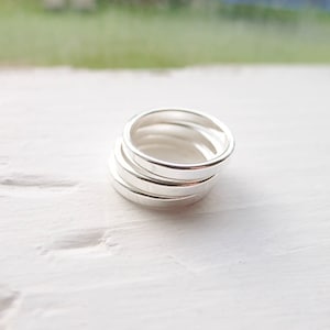 May include: Four silver stacking rings, each with a smooth, polished finish. The rings are stacked on top of each other, creating a simple and elegant look.