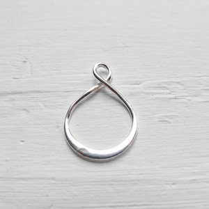 May include: A silver infinity pendant charm with a hammered finish. The pendant is shaped like a teardrop with a loop at the top for attaching to a chain or cord.