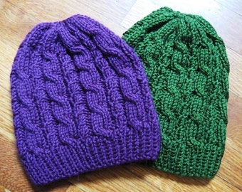 May include: Two knitted hats, one purple and one green, with a cable knit pattern.