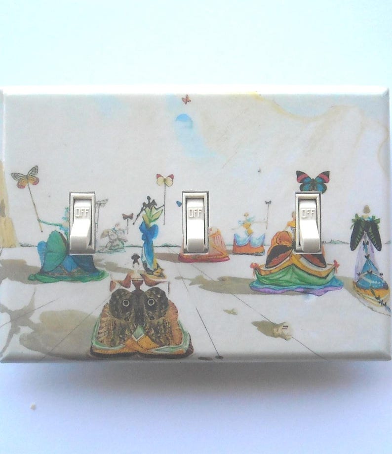 May include: A decorative light switch cover featuring a surrealist painting with butterflies and figures. The cover has three silver toggle switches, each labeled "OFF". The artwork includes a variety of colors, including blue, green, and orange.