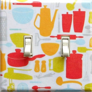 May include: A double light switch cover with a white background and a colorful kitchen utensil pattern. The pattern includes red pots, yellow bowls, and orange teapots. The switches are white and labeled "OFF".