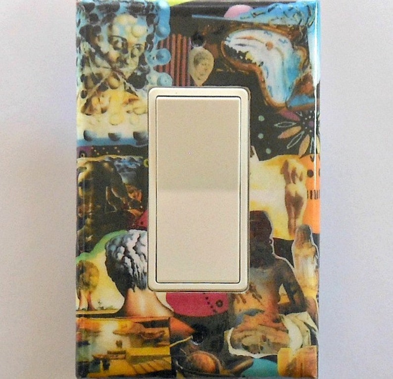 May include: A decorative light switch cover featuring a collage of surrealist art. The artwork includes images of figures, faces, and abstract shapes in a variety of colors, including blue, yellow, and red. The switch itself is white.