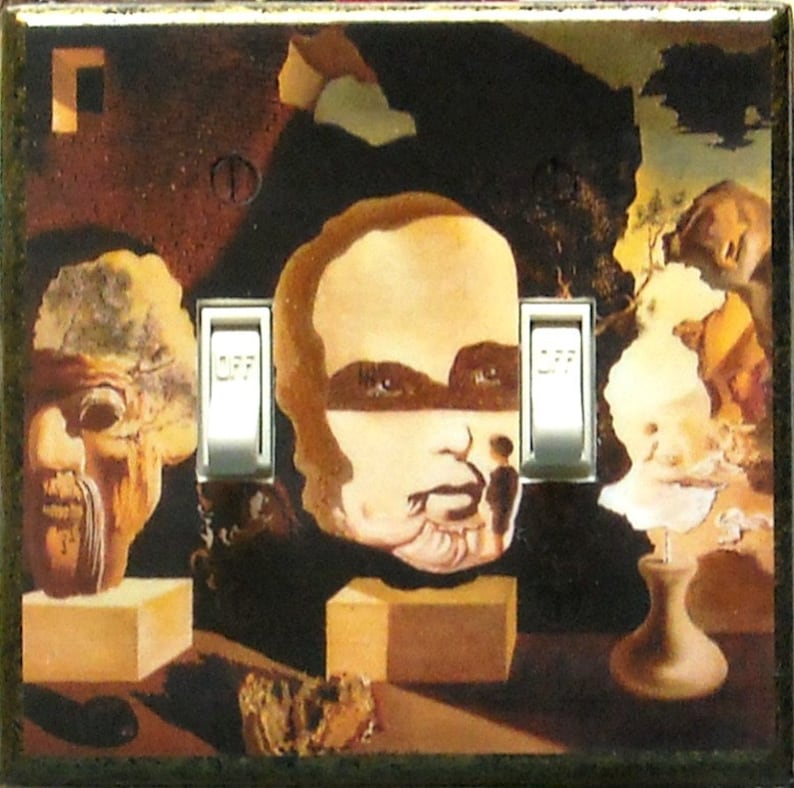 May include: A decorative light switch cover featuring a surrealist painting with three sculpted faces and two light switches. The artwork has a dark, earthy color palette with a vintage aesthetic.