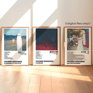 May include: Three framed posters featuring album art. The posters have a wooden frame and feature the text "digital files only". The posters are for Phoebe Bridgers albums: "Stranger in the Alps", "Punisher", and "Motion Sickness". Each poster has a unique color palette.