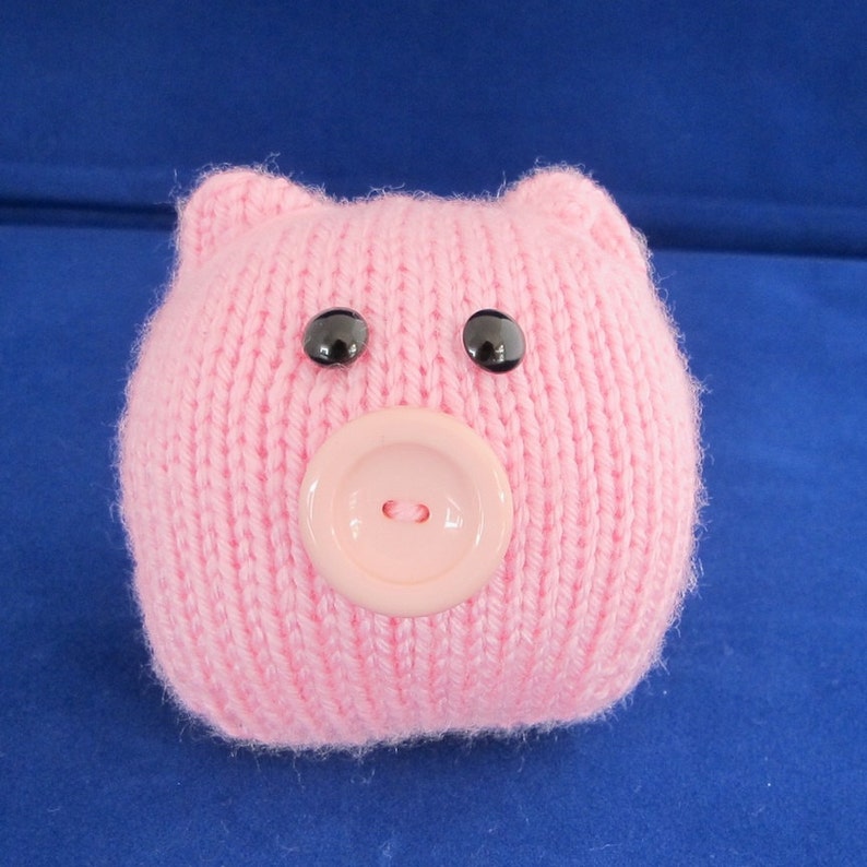 May include: A pink knitted pig with black eyes and a pink button nose.