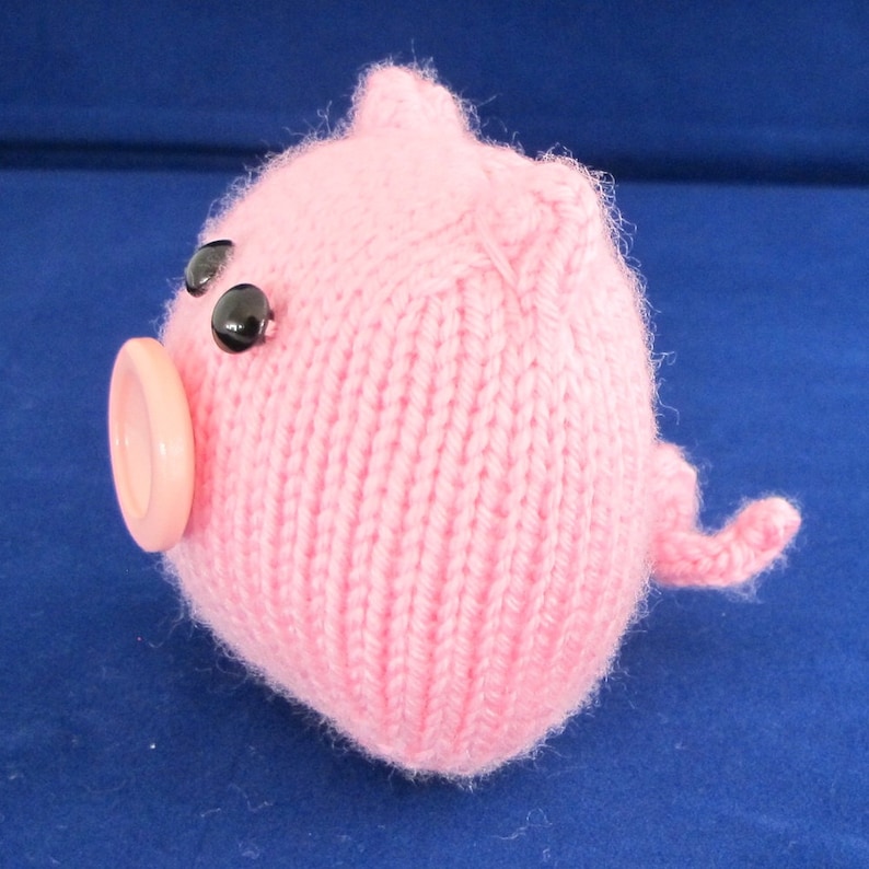 May include: A pink knitted pig toy with black eyes and a pink button nose.