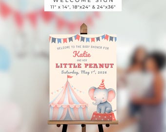 May include: A circus-themed welcome sign on an easel. The sign features a circus tent and an elephant wearing a party hat. Text includes "Welcome to the Baby Shower for Katie and her Little Peanut, Saturday, May 1st, 2026." Sign sizes are 11"x14", 18"x24", and 24"x36".