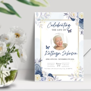 May include: A blue and white floral memorial card with a gold frame. The card features a photo of a woman and the text "Celebrating the Life of Kathryn Johnson, April 10th 1945 - November 11th 2024, Saturday, Nov 20, 11:00 AM, The New Life Church Any City, St 88770".