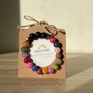May include: A colourful lava stone bead bracelet with a brown card that says "Verve & Vibe Lava Stone Beads" with a small star design. The card also says "love, stone, harmony, beauty, handcrafted, aroma,  healing".