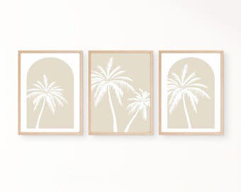 May include: Three framed art prints featuring white palm tree silhouettes on a beige background. Two prints have a rectangular shape, while the third has an arched top. The frames are made of light-colored wood, creating a minimalist aesthetic.